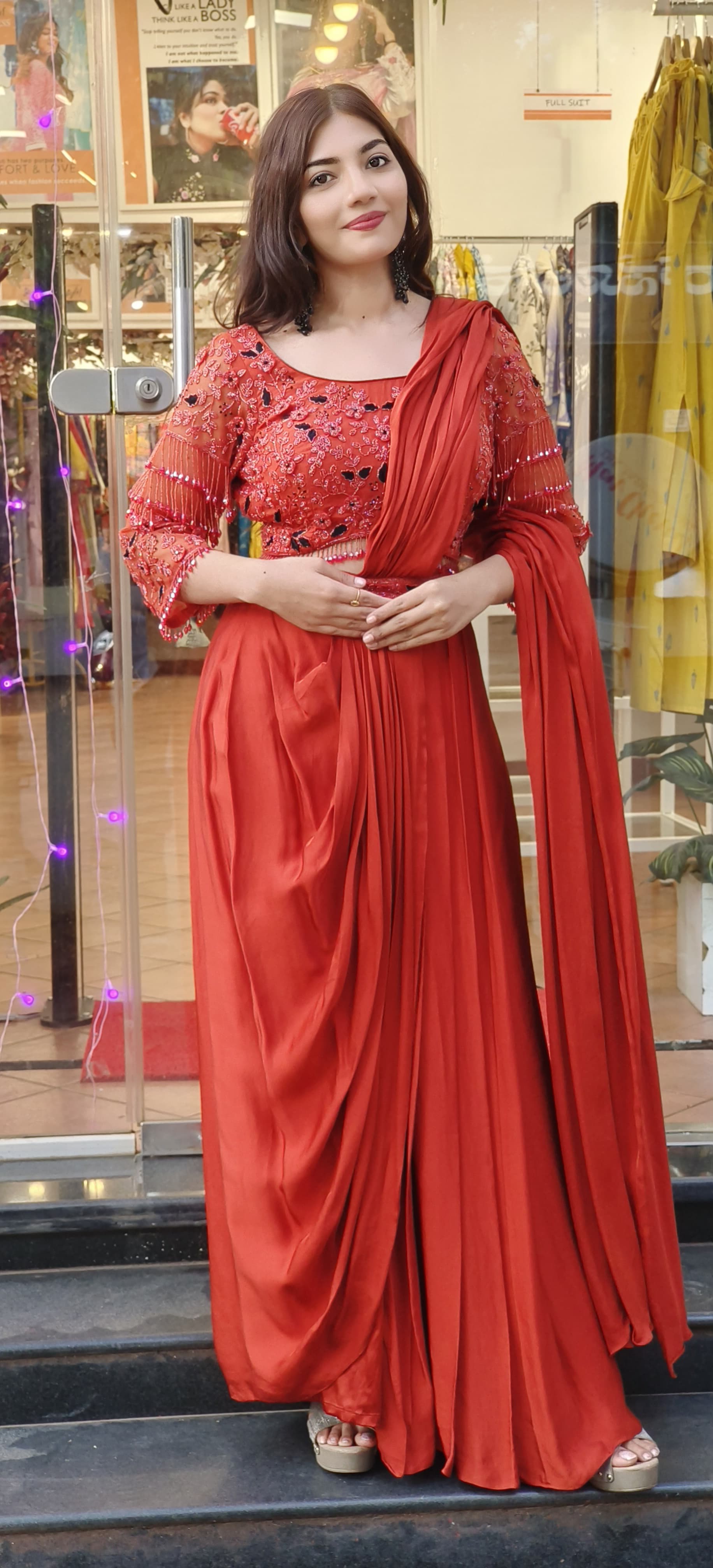 Rust Crystal-Embellished Crepe Dhoti Saree Set A designer ensemble featuring a heavily adorned crystal work blouse paired with a trendy drape dhoti-style saree DRY WASH-ONLY ON ORDERS DISPATCHING AFTER 30 DAYS -